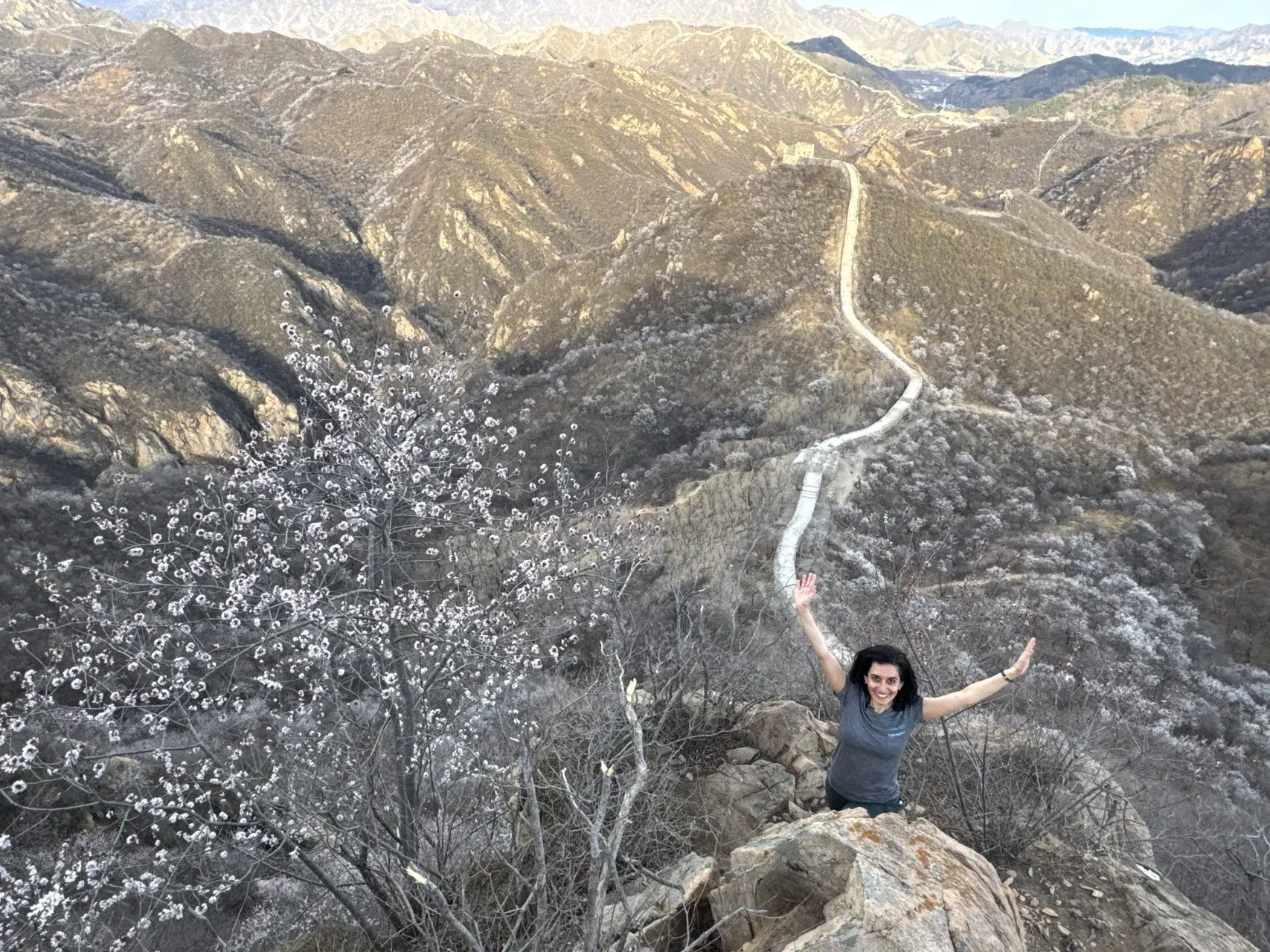 A hiker celebrating above the Wild Great Wall and mountain ridges near Beijing