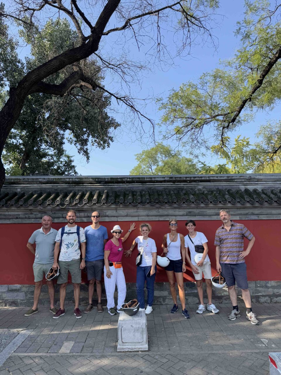 Beijing date night ideas – couples and friends on an Our Beijing Hutong Tour taking a photo in front of red walls
